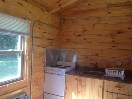 Cabin kitchenette with a stove and sink next to a window